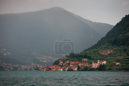 Téléchargez les photos : Village Carzano sur l'île de Monte Isola au lac d'Iseo en Italie, après-midi soleil sur les maisons colorées, pluie en arrière-plan. Juin 2023 - en image libre de droit