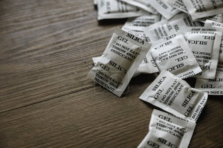 Photo for Desiccant or silica gel in white paper packaging on a wooden background. - Royalty Free Image