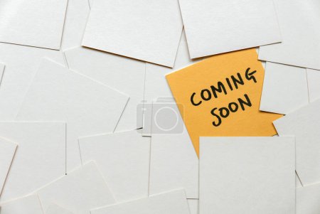 Photo for A yellow card among an empty white card written with coming soon. - Royalty Free Image