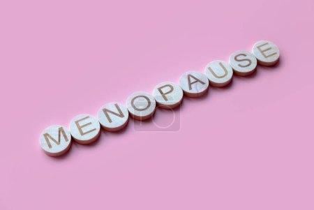 Foto de El alfabeto forma una palabra menopausia. Salud y concepto médico para las mujeres. Fondo rosa. - Imagen libre de derechos