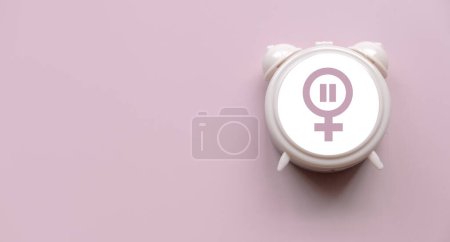 Foto de Concepto de menopausia. Mujeres símbolo sobre un reloj. Atención médica y de salud para las mujeres. Fondo rosa con espacio de copia. - Imagen libre de derechos