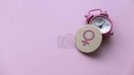 Concepto de menopausia. Mujeres símbolo sobre un reloj. Atención médica y de salud para las mujeres. Fondo rosa con espacio de copia.