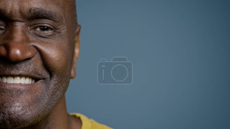 Téléchargez les photos : Gros plan moitié visage masculin avec expression joyeuse mature homme afro-américain regardant la caméra souriant blanc sain sourire heureux client satisfait du service posant en studio de fond gris - en image libre de droit