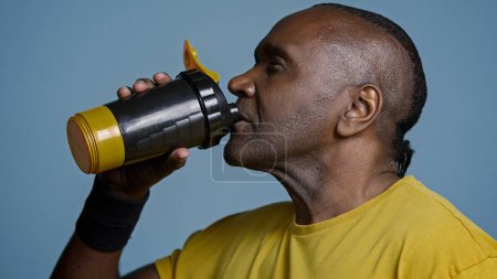 Photo for Close-up tired athletic man athlete taking break during training drinking cool fresh water from sports bottle quenches thirst after exercise adult african american sportsman enjoying protein drink - Royalty Free Image