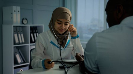 Téléchargez les photos : Arabe femme médecin infirmière mesure haute pression artérielle utilisation tonomètre écouter pouls du patient africain souffrent d'hypertension maladie cardiaque femme cardiologue examen vieil homme cardiologie check-up - en image libre de droit
