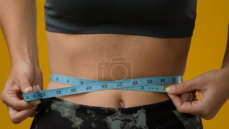 Photo for Close up female abdominal body part tummy cropped view unrecognizable sport woman with measuring tape measure waist unknown sporty slim lady girl fitness weight loss calories checking torso progress - Royalty Free Image