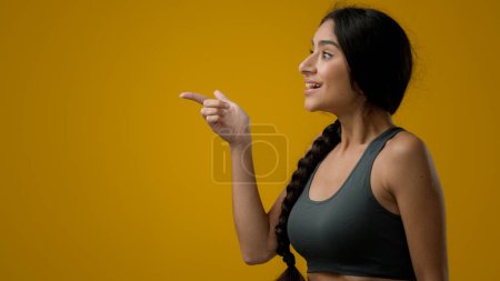 Téléchargez les photos : Je me demande surpris femme indienne surprise fille femelle en studio fond jaune pointant vers le côté pour vide espace de copie publicité étonnement étonnant regardant à côté étonnement incrédulité choc excité - en image libre de droit