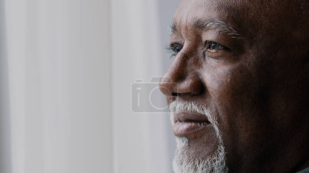 Photo for Close up pensive male old wrinkled face, 60s African bearded man deep in sad thoughts looking at window, elderly grandfather look away think about disability feel lonely. Nostalgia retired businessman - Royalty Free Image