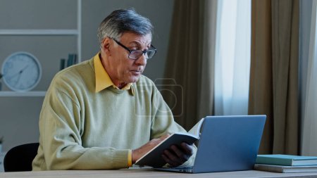 Photo for Senior older male online distant teacher webinar speaker tutor coach talking to webcam of laptop video training vlog online conference call old man holding notebook with notes reading information - Royalty Free Image