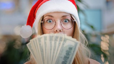 Foto de Mujer caucásica con sombrero rojo de Santa Navidad gorra y gafas con dólares de celebración de dinero feliz celebrar el éxito de compras regalo de bonificación recompensa premio financiero ganar chica dama disfrutar de descuento a Año Nuevo - Imagen libre de derechos