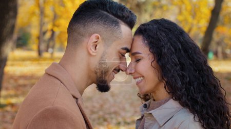Photo for Loving married couple standing foreheads touch and rubbing noses touching smiling outdoors multiracial man and woman ethnic girlfriend and boyfriend love tenderness on romantic date in autumn park - Royalty Free Image