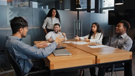 Photo for Multiracial business group in office meeting discuss project startup. Men and women coworkers partners team brainstorming ideas discussing marketing strategy at boardroom. Multiethnic company leaders - Royalty Free Image