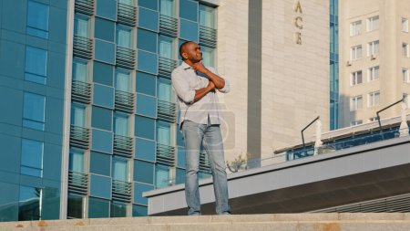 Photo for Ethnic pensive thinking African American middle-aged senior mature man thoughtful male businessman investor entrepreneur think business idea standing in city outdoors on office building background - Royalty Free Image