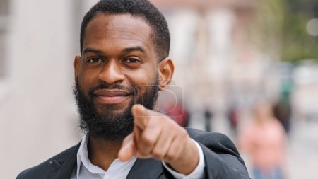 Foto de Close up ethnic African American man entrepreneur employer male HR manager CEO businessman in city outdoors pointing with forefinger direction to camera hey you support agree gesture choosing sign - Imagen libre de derechos