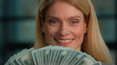 Photo for Caucasian rich middle-aged adult woman close up headshot female face with banknotes fan of money indoors. Winner mature lady businesswoman holding business cash profit finance dollars smiling happy - Royalty Free Image