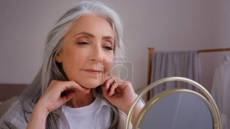 Foto de Portrait old senior mature lady granny model enjoy shampoo recovery result 60s years aged Caucasian woman recovery long hair touching healthy gray silver hairdo haircare procedure looking at mirror - Imagen libre de derechos