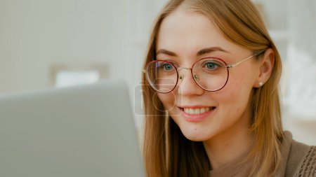 Foto de Close up Caucasian woman female face girl in glasses eyes look at laptop screen. Freelancer smiling businesswoman busy with computer work studying bad eyesight vision laser correction surgery concept - Imagen libre de derechos
