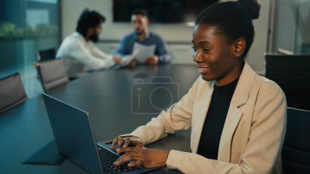 Foto de African American businesswoman multiracial woman manager consultant marketer leader ethnic company CEO talk video call conference waving hello in office table on blurred background of male colleagues - Imagen libre de derechos