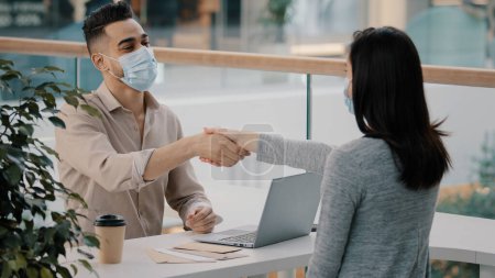 Foto de Man bank worker insurance agent man in medical mask advises consulting girl woman client about loan give cash money dollars credit shaking hands currency exchange financial services consultation. High - Imagen libre de derechos