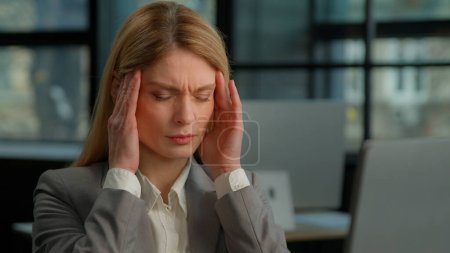 Photo for Caucasian middle-aged 40s adult woman office worker executive tired sick ill business female lady businesswoman working with computer holding painful head feeling pain headache migraine ache unwell - Royalty Free Image