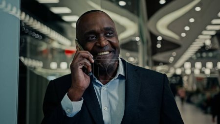 Photo for Middle-aged smiling African American entrepreneur ethnic man businessman indoors answer call listening good news mobile phone calling talk victory achievement winning smartphone talking business offer - Royalty Free Image