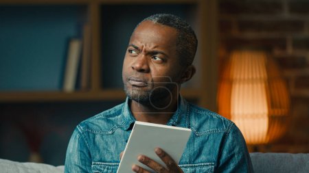 Foto de Pensive adult african american man indoors thinking deep in thoughts create strategy thoughtful businessman making notes in notebook planning searching for solution writing down idea write memories - Imagen libre de derechos