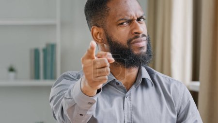 Foto de Furious mad angry aggressive bearded African American businessman in office close up professional manager employer man office worker pointing finger at camera threat gesture warning with hand hey you - Imagen libre de derechos