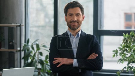 Téléchargez les photos : Successful smiling caucasian adult businessman leader stand in office with crossed arms confident executive man company leader ceo professional manager looking at camera posing for business portrait - en image libre de droit