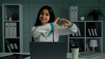Photo for Caring sincere young woman arabian latina cardiologist medical student cardiology medicine doctor make love symbol heart organ shape demonstrate human generosity care support charity donation concept - Royalty Free Image