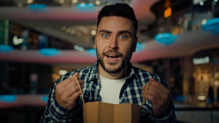 Foto de Surprised happy businessman caucasian man male client shopper look at bags with presents win surprise gift on birthday get delivery packages purchases from shop supermarket buy cloth in shopping mall - Imagen libre de derechos