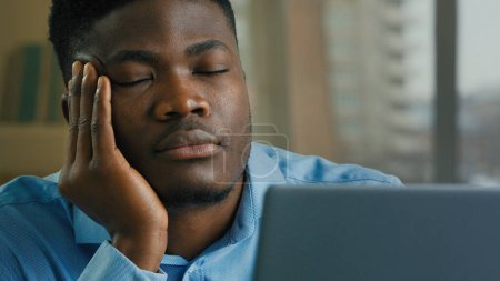 Photo for Sleepy overworked tired african american man employee manager businessman fall asleep at office desk sleeping napping exhausted guy resting with eyes closed feeling exhaustion lack of sleep after work - Royalty Free Image