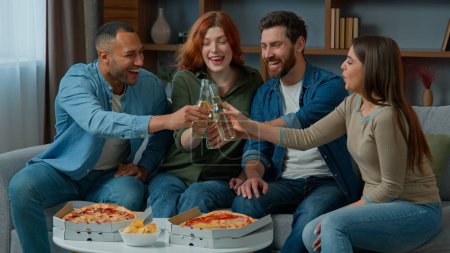 Photo for Group of happy multiethnic diverse friends having fun clinking bottled beer at home drinking alcohol at festive table with pizza adults people celebrate together Friday party birthday new year holiday - Royalty Free Image