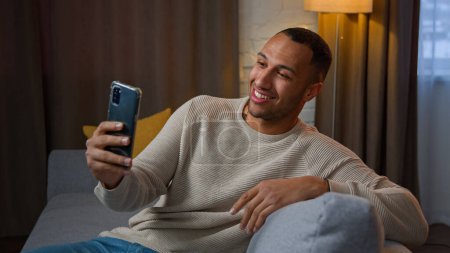 Photo for African american latino ethnic man multiracial businessman blogger freelancer millennial 30s user talking in mobile webcam chat record video blog on phone selfie camera friendly virtual talk at home - Royalty Free Image