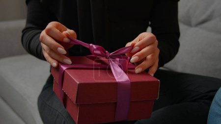 Photo for Close up presenting gift on marriage anniversary Valentine love day romantic date unrecognizable female hands unpacking surprise pink box take off ribbon. Cropped view couple man and woman get present - Royalty Free Image