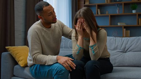 Téléchargez les photos : Guilty african american man apologizing to crying woman caring husband boyfriend calm sad stressed wife consoling girlfriend supporting saying sorry asking forgiveness after conflict family quarrel - en image libre de droit