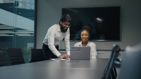 Indian Arabian mentor businessman leader man helping African American female woman worker businesswoman teach intern explain online business corporate software with laptop. Colleagues working together