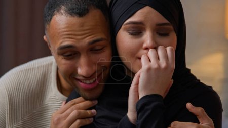 Téléchargez les photos : African american man care about sad offended crying arabian muslim woman diverse multiracial couple sit indoors loving husband calming wife cuddling apologize support empathy family relation problem - en image libre de droit
