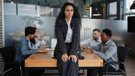 Photo for Worried upset leader woman tired worker businesswoman sitting on table in conference room sad with business problem failure multicultural team diverse colleagues in background discussing work project - Royalty Free Image