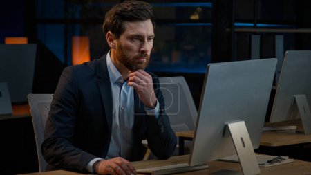 Téléchargez les photos : Pensive Caucasian middle-aged man sit at night office thinking deep thought dreaming new project business idea brainstorm solve problem thoughtful male businessman thinking search solution in computer - en image libre de droit