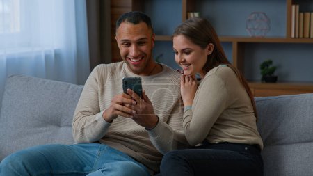 Foto de Multiracial couple african american man and hispanic woman win game on mobile phone read good news get bank loan mortgage online happy male female use smartphone app winning lottery internet discounts - Imagen libre de derechos