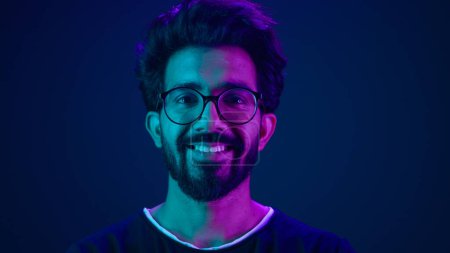 Téléchargez les photos : Portrait Homme indien musulman gars développeur codage travailleur sourire ordinateur technologie internet pirate Arabe mâle dans des lunettes souriant bleu néon ultraviolet studio fond high-tech futur cyberespace - en image libre de droit