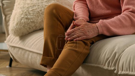 Photo for Caucasian ill unhealthy suffering old woman at home couch elderly female suffer from knee pain ache senior retired lady grandmother feeling bad injury painful leg on sofa osteoarthritis health problem - Royalty Free Image