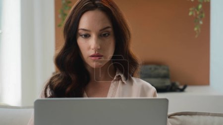 Photo for Focused Caucasian woman at home office looking at laptop girl use new app pensive thinking reading email work on research project online on computer make remote business task think of problem solution - Royalty Free Image