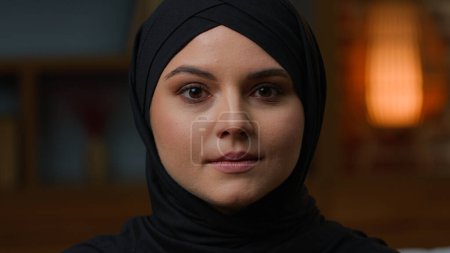 Téléchargez les photos : Tête abattue Arabe musulmane jeune fille islamique en hijab noir Moyen-Orient orientale dame islam religion. Gros plan visage en foulard beauté maquillage soin de la peau. Portrait féminin saudi malheureux à la maison - en image libre de droit