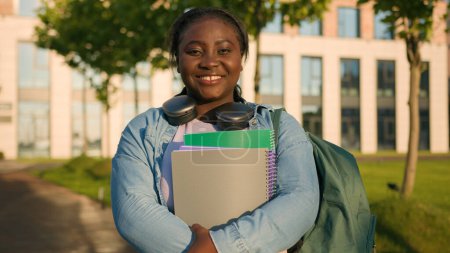 Photo for Portrait African American woman university college campus academy student teen girl high school pupil holding books with schoolbag headphones smiling toothy joyful in city outdoors study education - Royalty Free Image