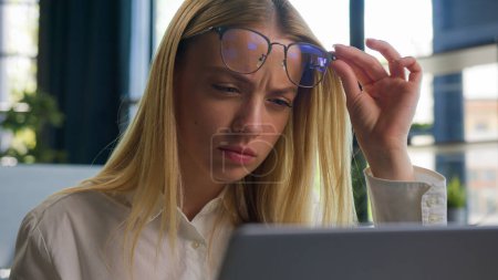 Téléchargez les photos : Femme d'affaires caucasienne confus dans les lunettes femme d'affaires employé enlever les lunettes problème mauvaise vision vision floue lecture sur ordinateur portable surmenage dans le bureau vérifier ophtalmologie service - en image libre de droit