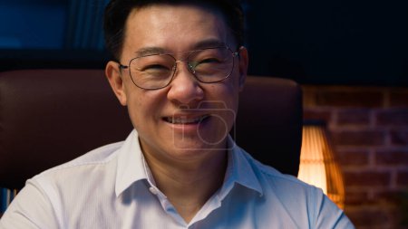 Photo for Close up business portrait Asian man Korean businessman worker middle-aged employer entrepreneur wear glasses executive in eyeglasses smiling happy smile to camera at night office at evening home - Royalty Free Image