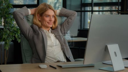 Photo for Smiling calm relaxed resting business woman finished computer work stretching sitting at desk in office. Happy middle-aged businesswoman satisfied after online complete job putting hands behind head - Royalty Free Image