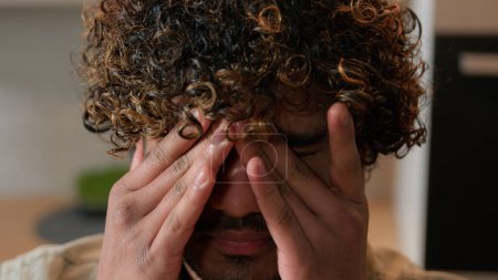 Téléchargez les photos : Gros plan Indien malade fatigué somnolent homme avec les cheveux bouclés frotter les yeux secs Arabe épuisé malade gars homme d'affaires à l'intérieur souffrent frotter fatigue oculaire mal de tête mal de vue astigmatisme ophtalmologie - en image libre de droit