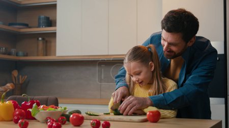 Photo for Caucasian father dad help teach show little child girl cute daughter cut vegetables salad cooking together teaching cutting cucumber explain how using knife happy family parental control at kitchen - Royalty Free Image